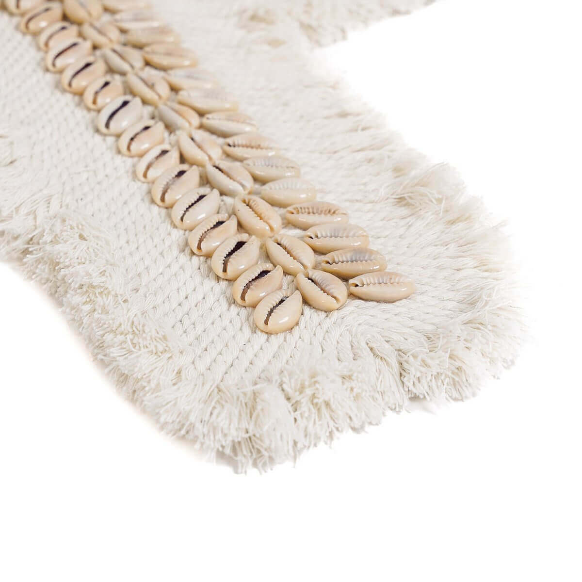 Detail van het witte macrame kruis met kaurischelpen en franjes, handgemaakt decorstuk van katoen.