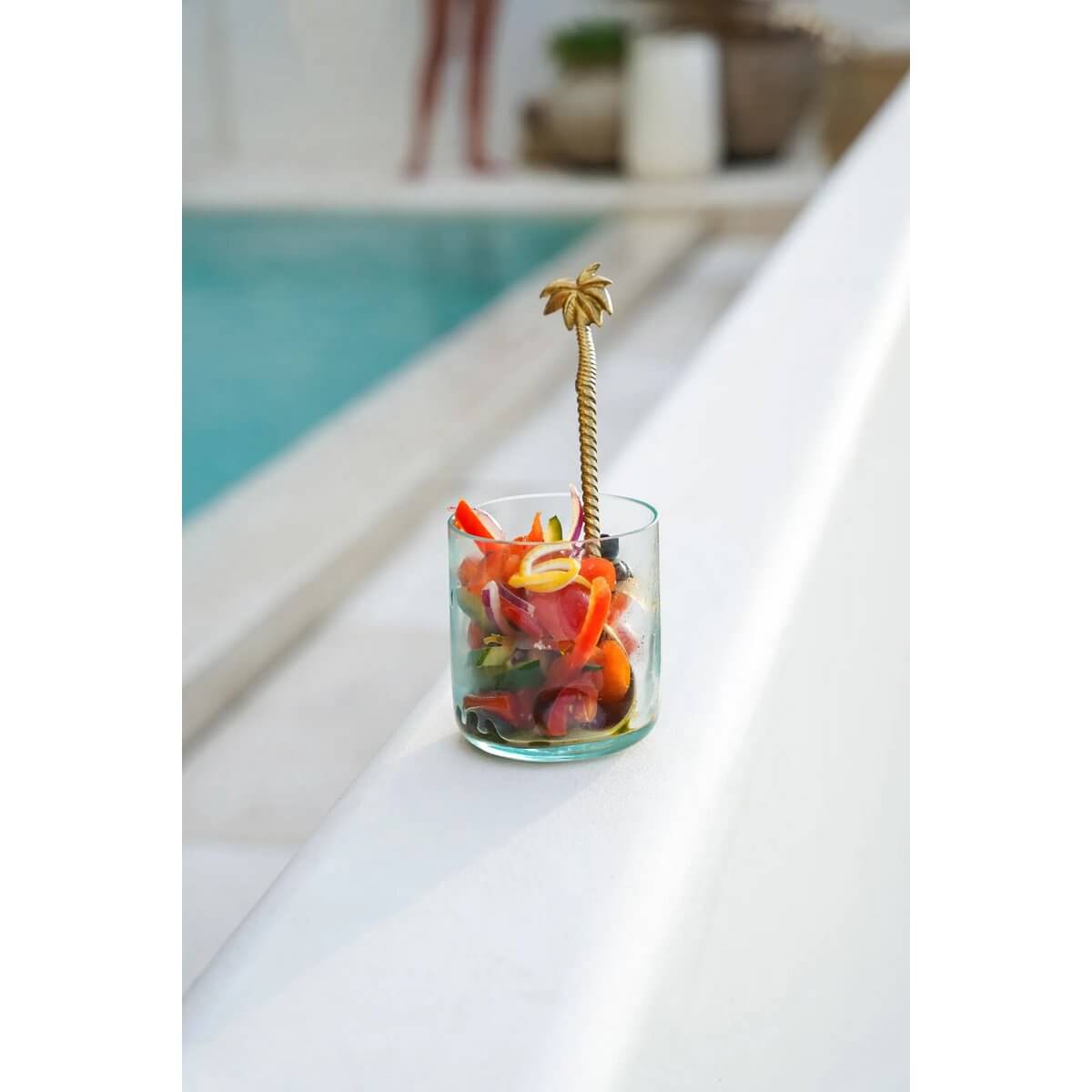 Bohemian On the Rocks glass made from recycled glass by the pool, filled with colorful vegetables and a palm tree stirrer.