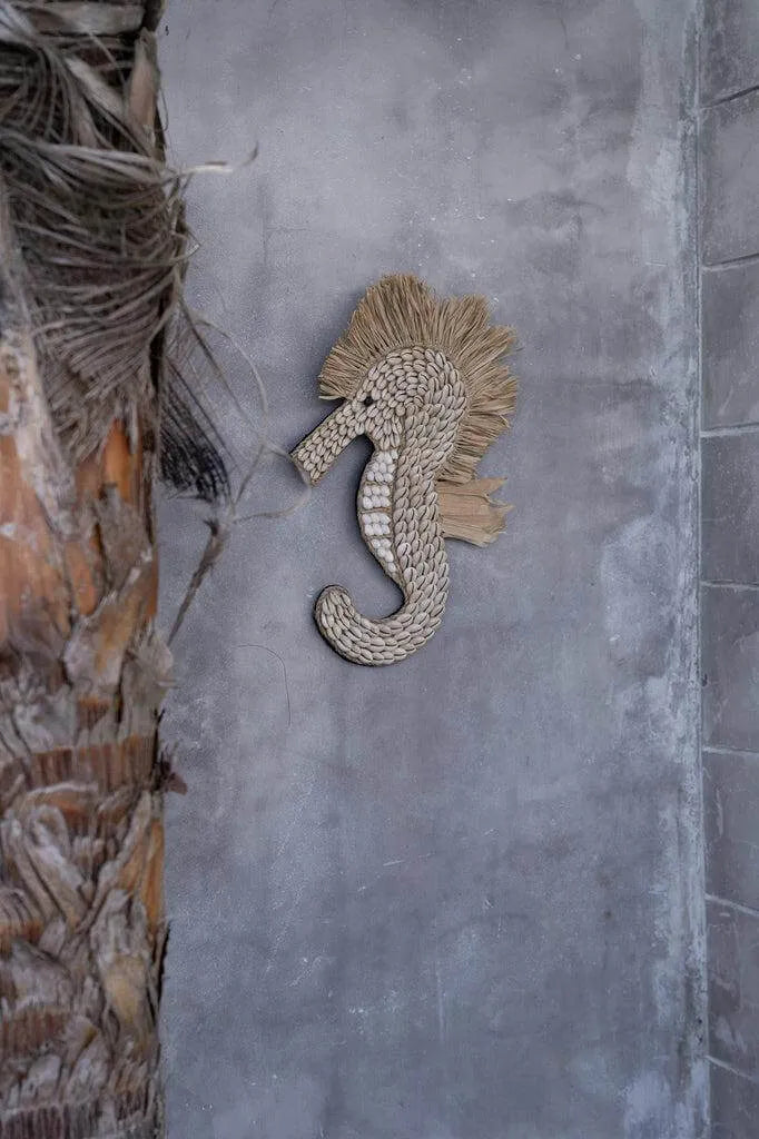 Decoratief wit zeepaardje van schelpen met raffia franjes, perfect voor ophangen als uniek interieuraccessoire.