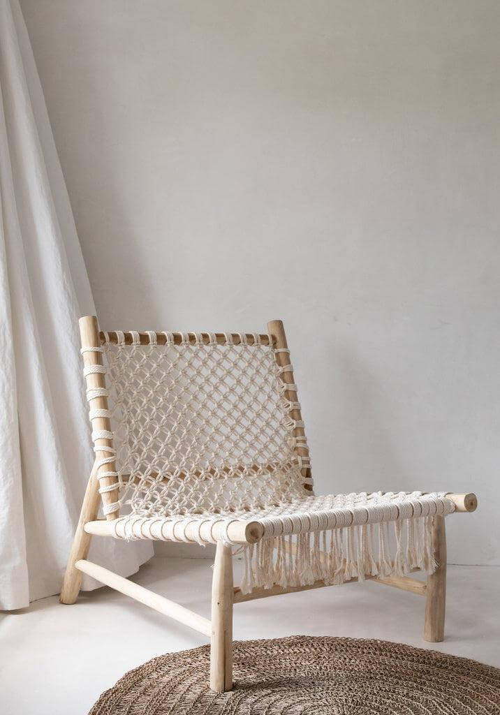 Handgemaakte houten stoel op een beige zeegras tapijt, voegt natuurlijke charme toe aan interieur.