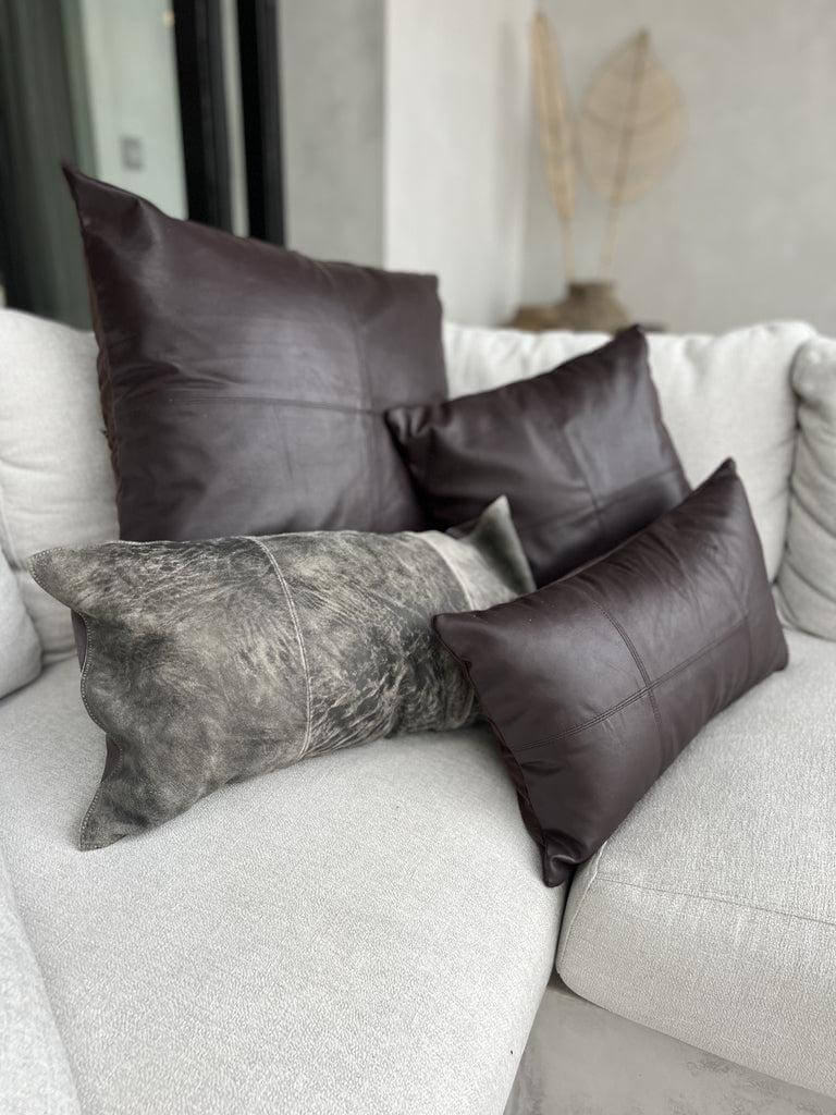 Luxe chocoladekleurige lederen kussenhoezen op een elegante witte bank, perfect voor een stijlvolle inrichting van elke ruimte.