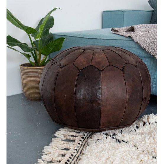 Chocoladebruine leren poef (XL) naast een blauwgroene bank, perfect voor een gezellige boho sfeer in huis.