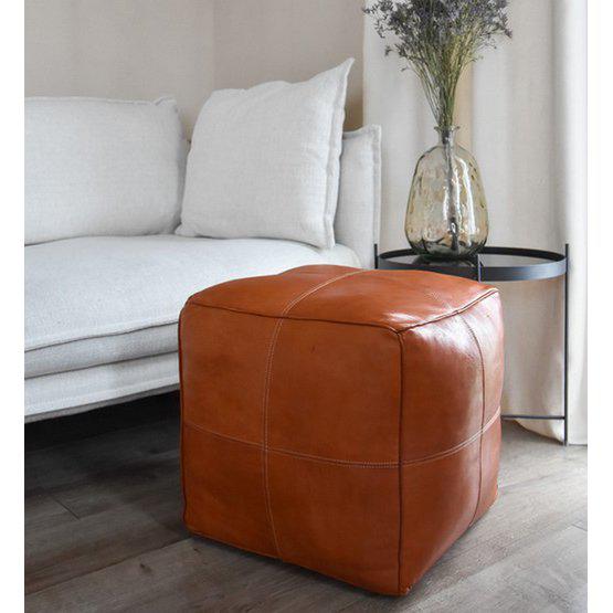 Vierkante leren poef in cognacbruin naast bank en vaas, perfect voor boho-stijl, woonkamer decoratie of extra zitplek.