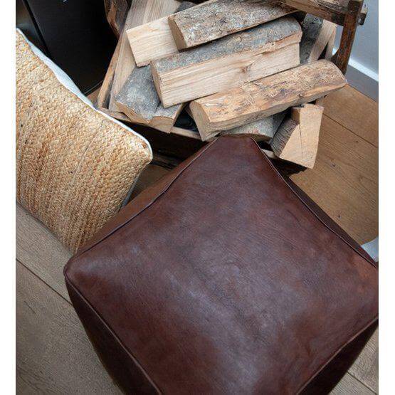 Marokkaanse donkerbruine leren poef, handgemaakt in XL formaat, vierkant, naast haardhout en decoratieve kussens in woonkamer.