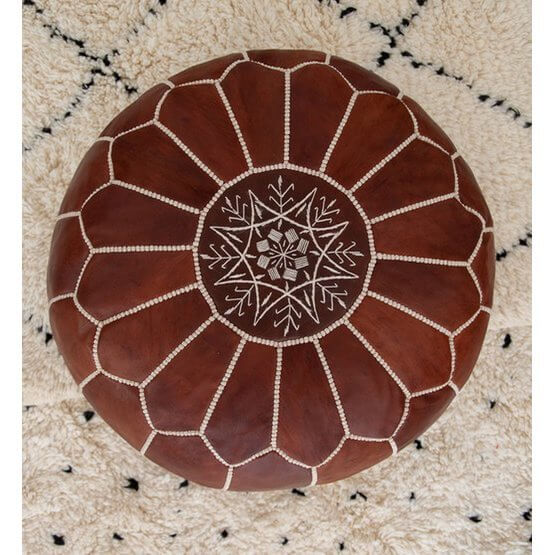 Handgemaakte Marokkaanse leren poef in honingbruin op vloerkleed, perfect voor boho interieur, voetenbankje of zitplaats.