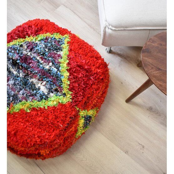 Marokkaans Boucharouite vloerkussen in levendige kleuren naast een houten tafel en stoel