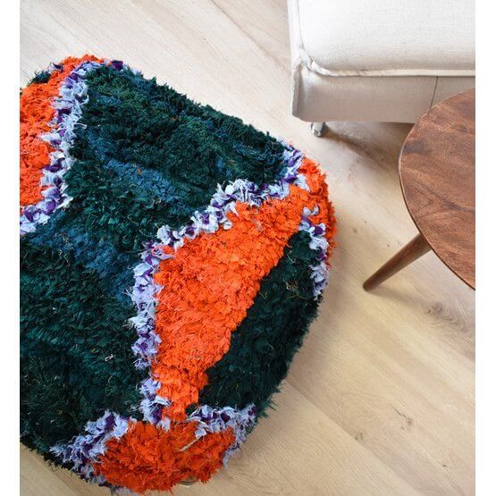 Levendig Marokkaans Boucharouite vloerkussen in kleurrijk design, handgemaakt van gerecycled textiel op een houten vloer.