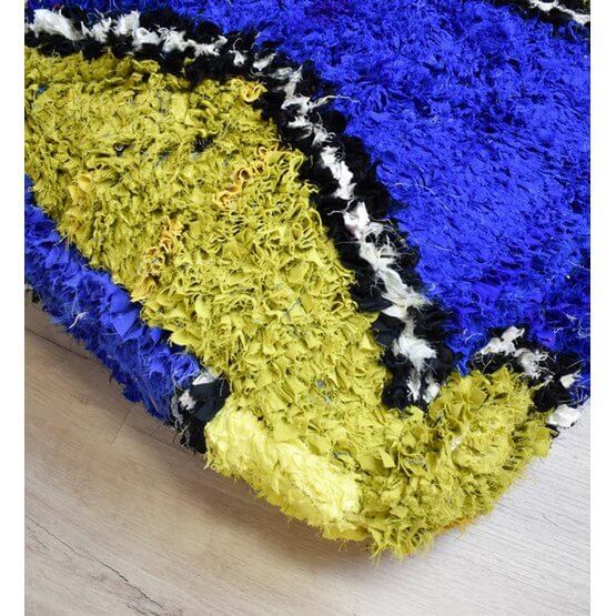 Kleurrijk Marokkaans Boucharouite vloerkussen met blauwe en gele patronen, handgemaakt van gerecycled textiel.
