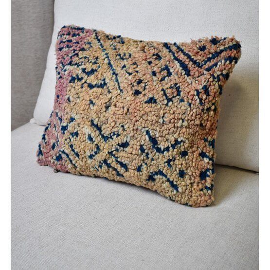 Vintage Marokkaans kussen op bank, unieke handgemaakte Berberstijl, beige en blauwe tinten voor woon- of slaapkamerdecoratie.