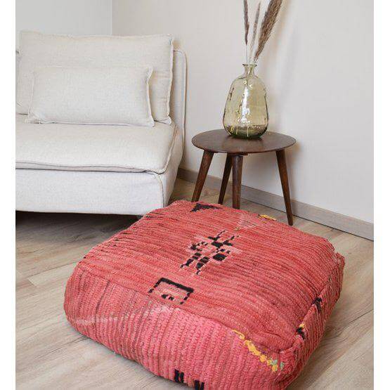 Marokkaans vloerkussen - K844 in een bohemian interieur met rode vintage stof en unieke Berberpatronen naast een moderne fauteuil.