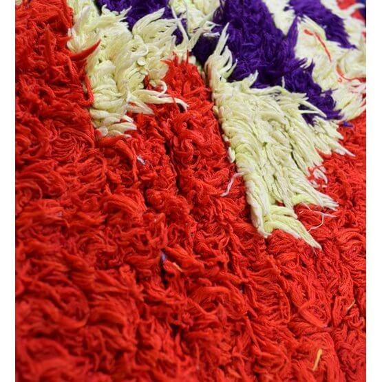 Close-up van kleurrijk Marokkaans vloerkussen van vintage berberkleed. Rood, geel en paars accentueren de unieke textuur.