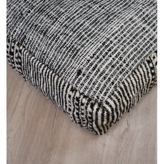 Marokkaans vloerkussen Zanafi K114 in zwart-wit patroon op houten vloer, handgemaakt en uniek, bohemian stijl interieurinspiratie.