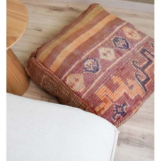 Marokkaans vloerkussen k700 met bohemian design, gemaakt van vintage Berberkleed, gelegen op een houten vloer naast witte meubels.