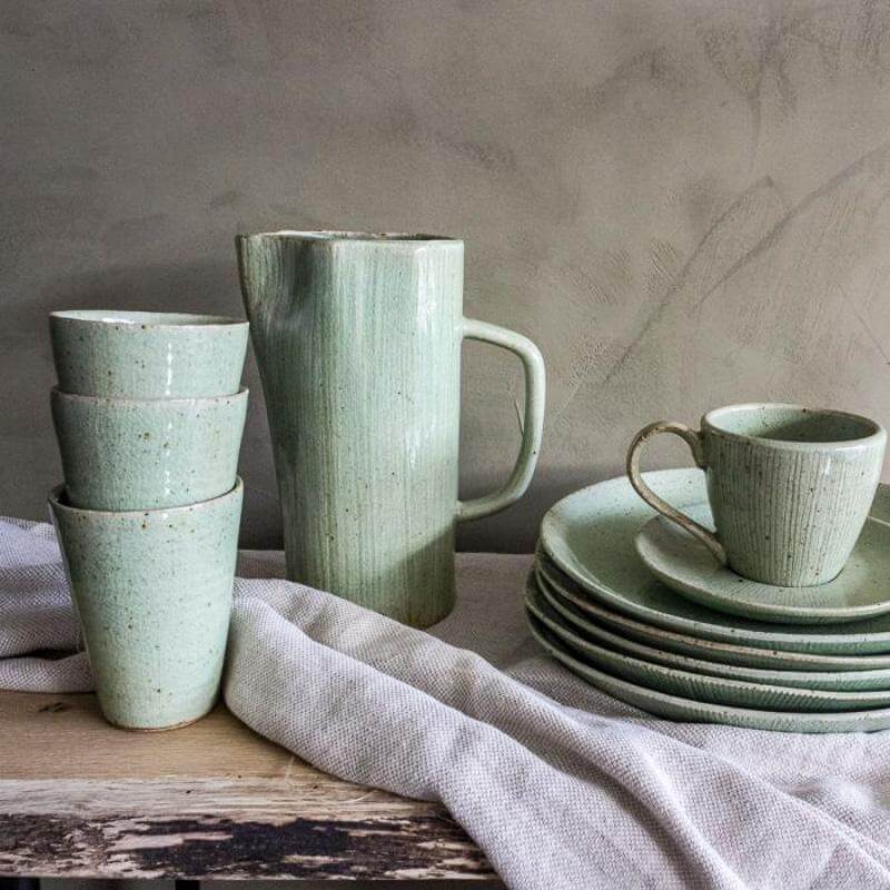 Frisgroen stoneware servies met mokken, borden en karaf. Perfect voor een sfeervol ontbijt of thee moment. Sterk en stijlvol ontwerp.