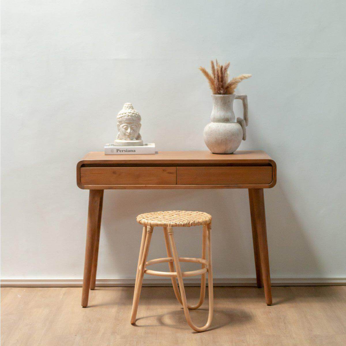Rotan Kruk KOLAKA Naturel Ø35 cm voor een rustieke touch in huis met geweven zitvlak en drie poten, naast een houten tafel.