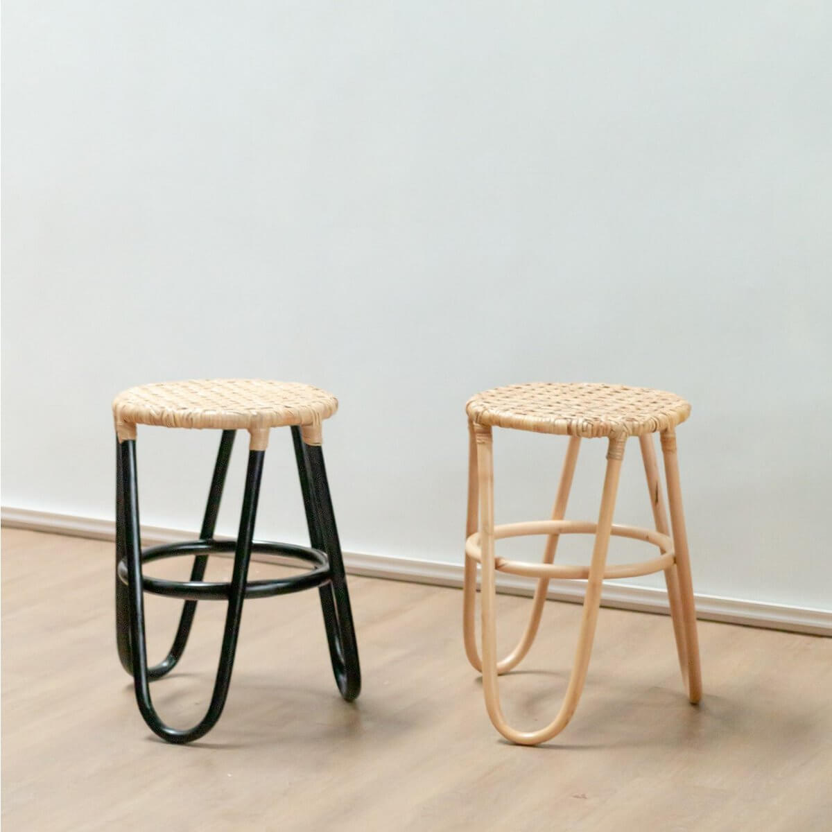 Twee rotan krukken KOLAKA met geweven zitvlak, in naturel en zwart, Ø35 cm op houten vloer.