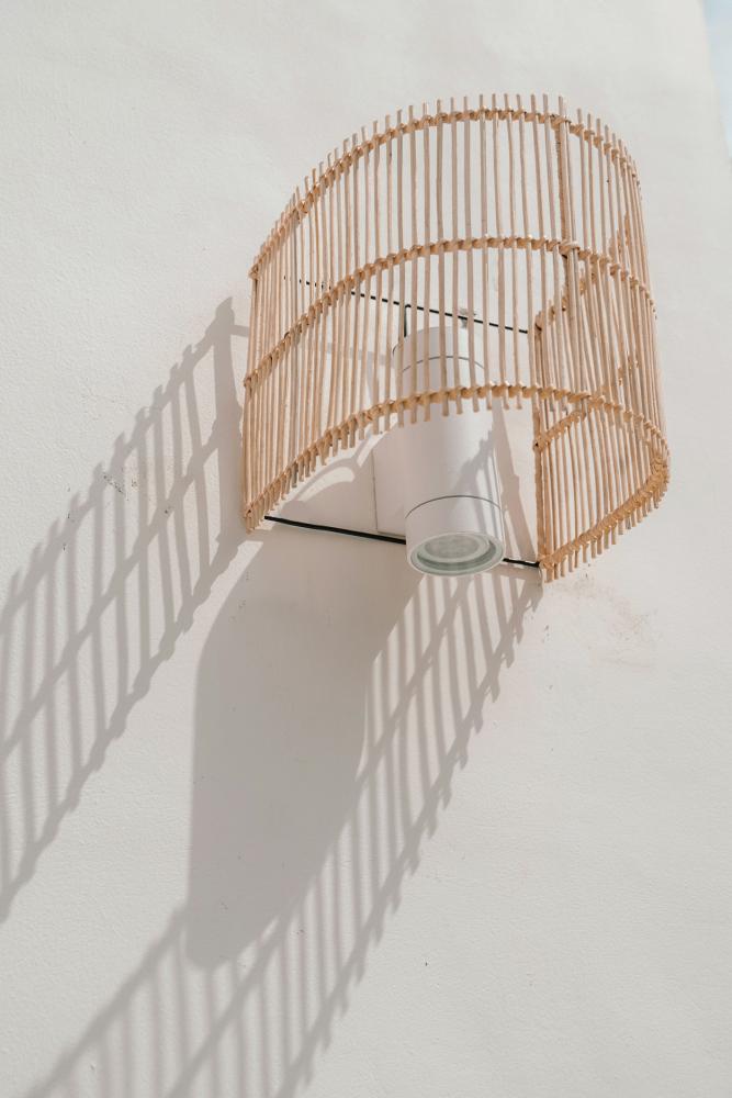 Rotan wandlamp de Gigi, halfcilindrisch design, creëert intieme sfeer met natuurlijke materialen.