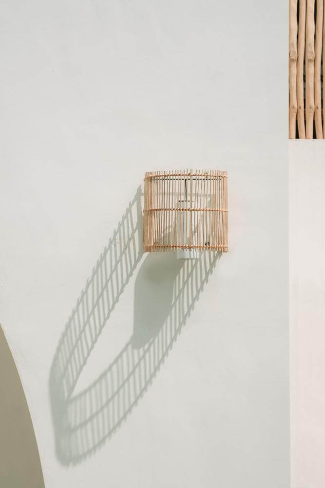 Rotan Wandlamp de Gigi aan een muur, creëert een intieme en gezellige sfeer met een elegante halfcilindrische vorm.