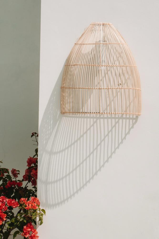 Rotan wandlamp de Lalo, creëert een intieme sfeer met zijn conische vorm, perfect voor een duurzame en gezellige interieurverlichting.