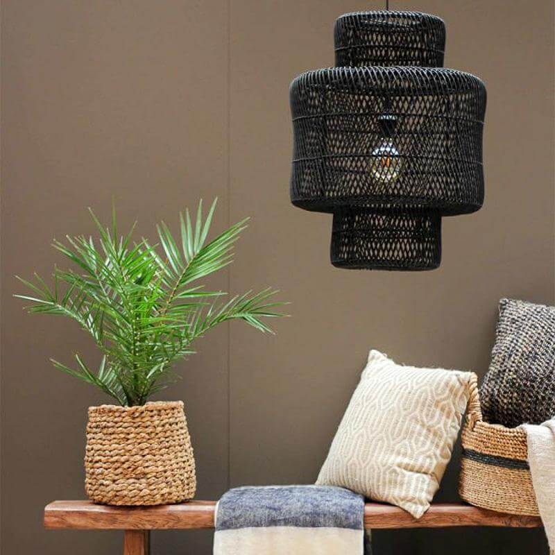 Rotan hanglamp Janine creëert boho sfeer in een rustiek interieur, gecombineerd met groene plant en kussens op houten bank.
