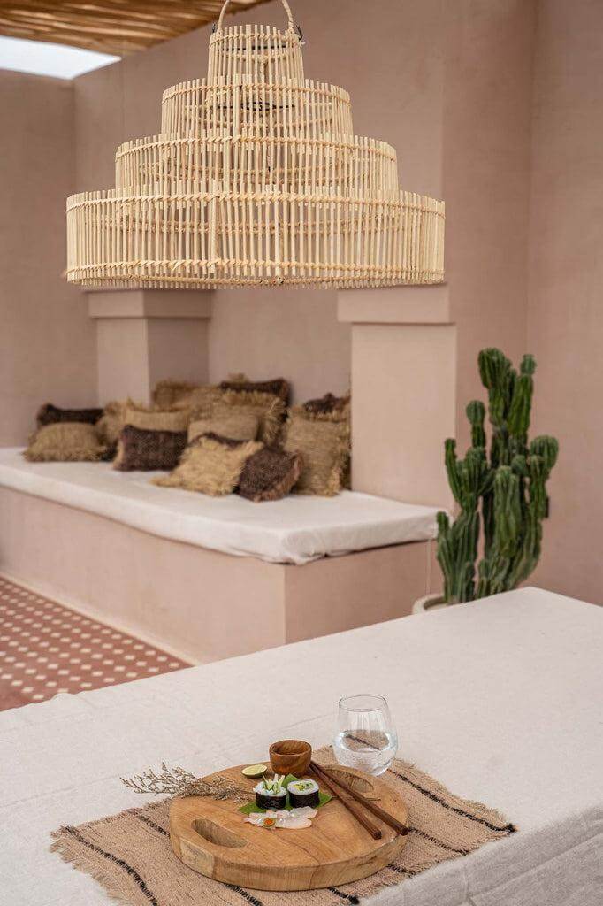 Rotan hanglamp in bruidstaart model hangt boven tafel met decor in boho-stijl, perfect voor sfeervolle woonkamers.