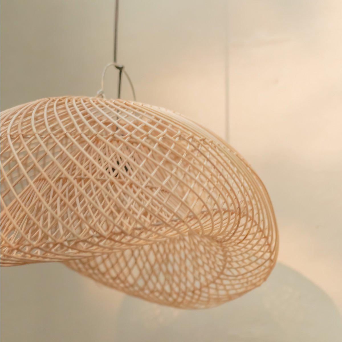 Rotanlamp PADMA in ovale vorm, handgemaakt van duurzaam rotan, werpt warme patronen op de muur. Verkrijgbaar in twee maten in Bali-stijl.