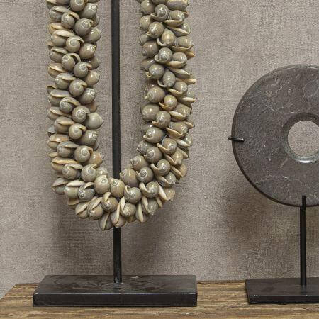 Moderne grijze schelpenketting op standaard, perfect voor een exotische sfeer in huis. Elegant decor met zwart statief.
