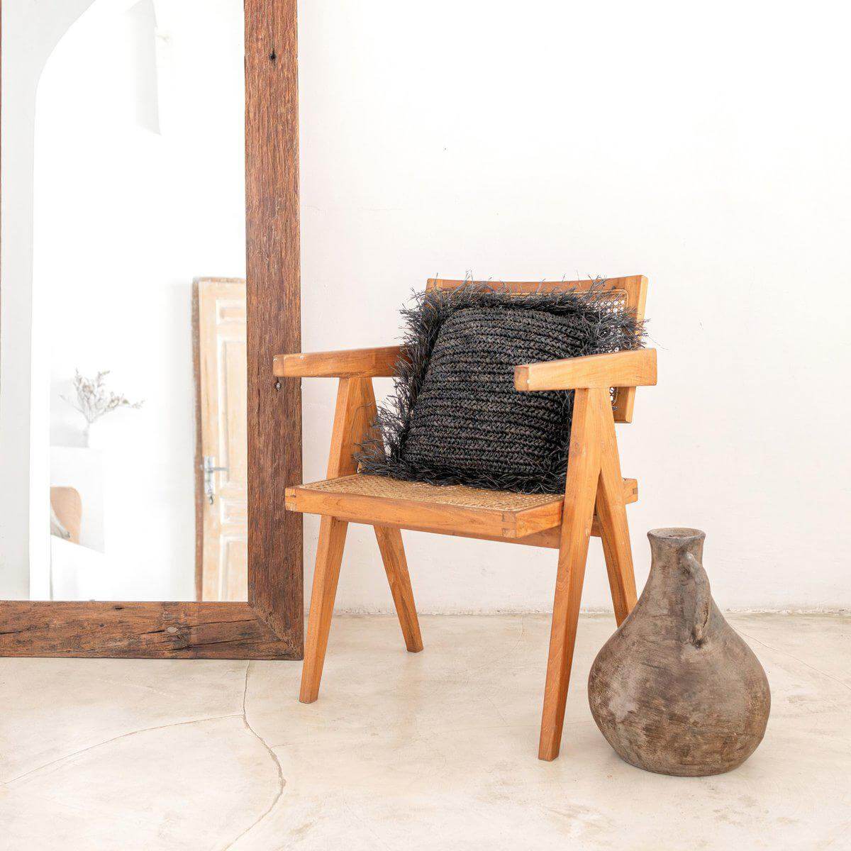 Stijlvolle Raffia sierkussen GANDI op houten stoel, perfect als decoratieve blikvanger in minimalistisch interieur, handgemaakt en duurzaam.