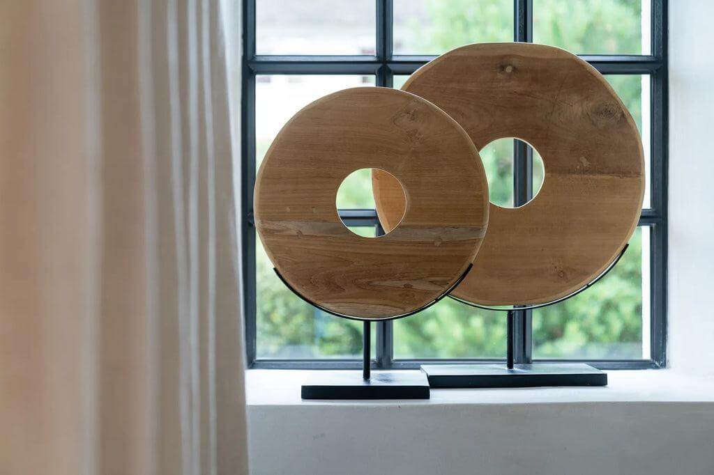 Teakhouten cirkels op standaard voor een Ibiza interieur, gemaakt van eco-vriendelijke materialen, in een rustieke raamdecor setting.
