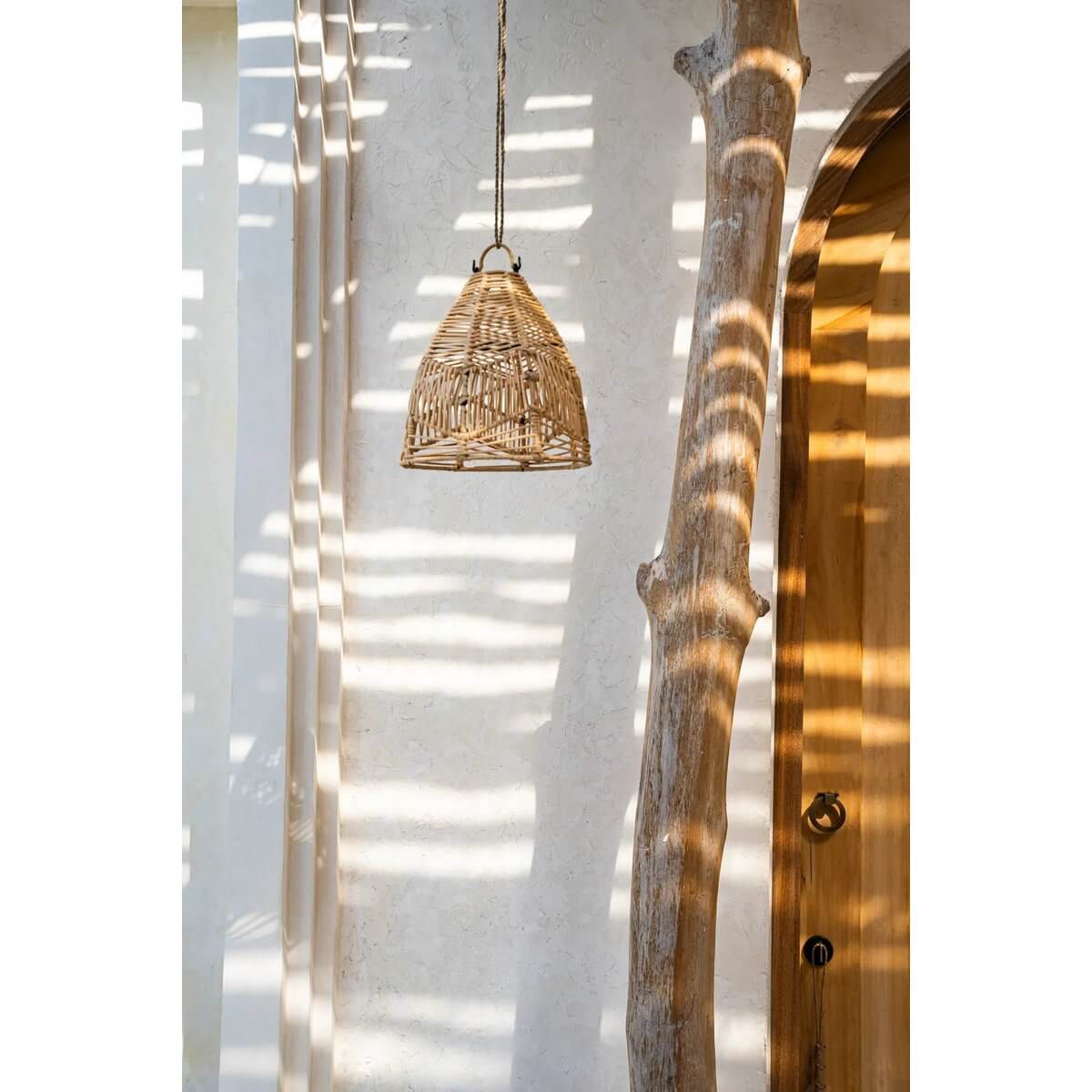 Handmade Bala rattan pendant lamp in bohemian style hanging on a wall with natural light shadows, perfect for bedrooms or patios.
