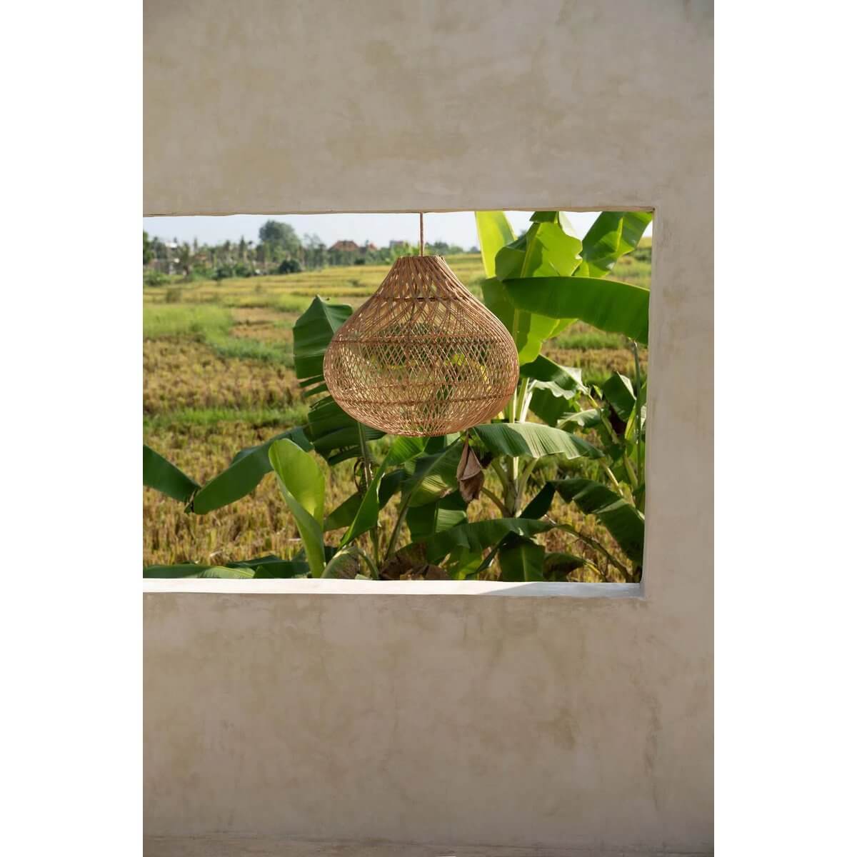 Rotan hanglamp "The Bottle Hanger - Naturel M" in boho stijl, geschikt voor slaapkamer of tuin, met uitzicht op groene velden.