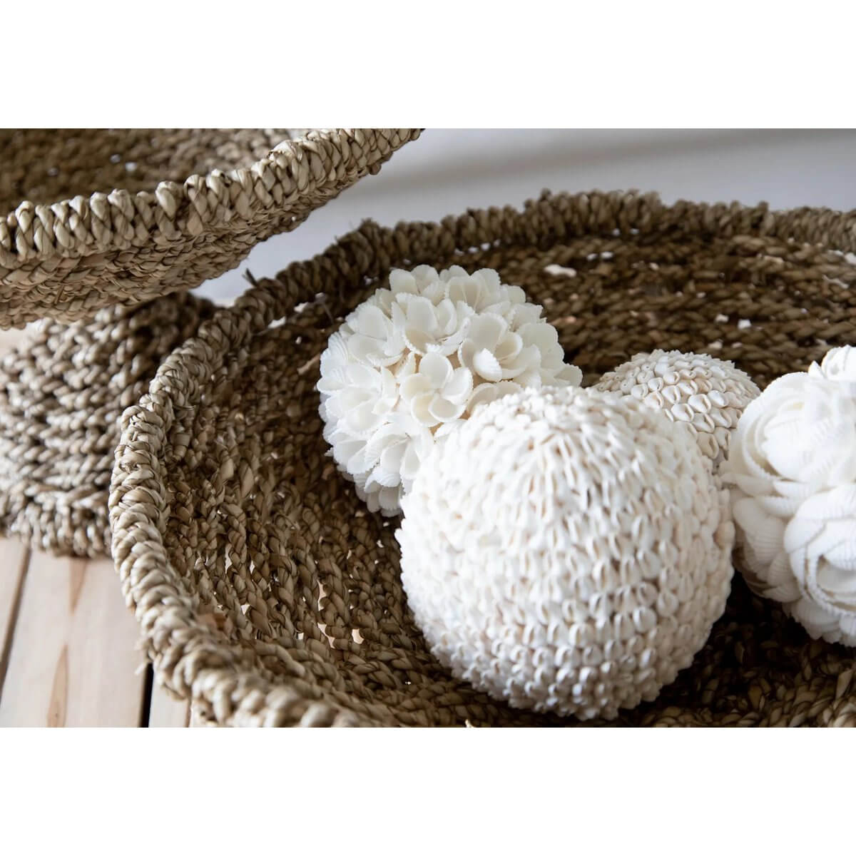 Handmade white bubble shell balls displayed in woven baskets, perfect for bohemian decor. Unique decor pieces by Balinese craftsmen.