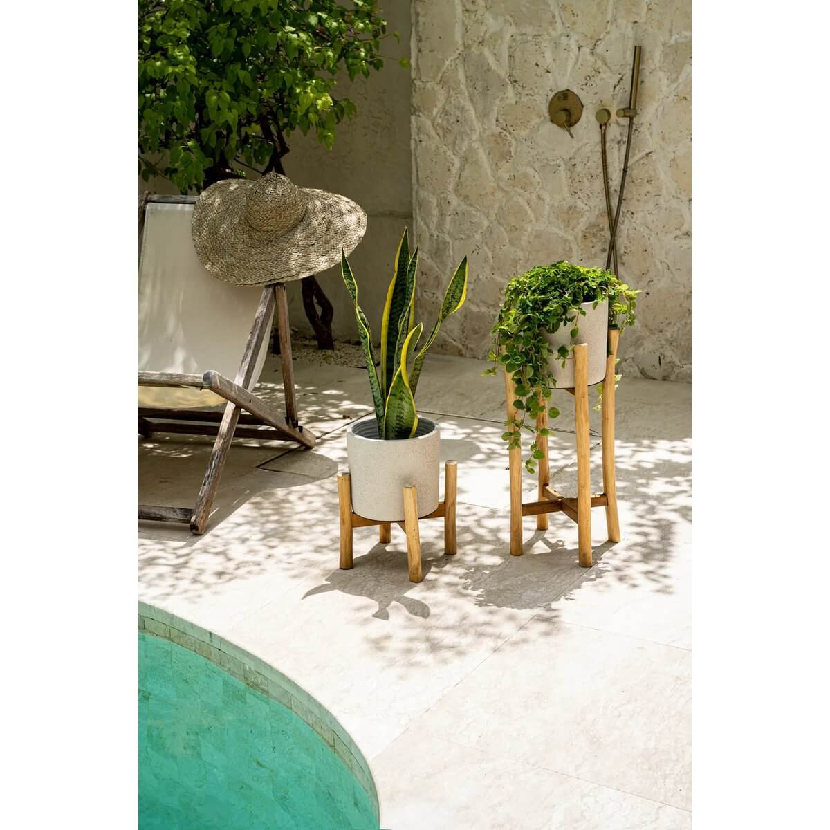 Bohemian-style outdoor setup with terracotta planter on teak stand, lush greenery, and tropical ambiance by the pool.