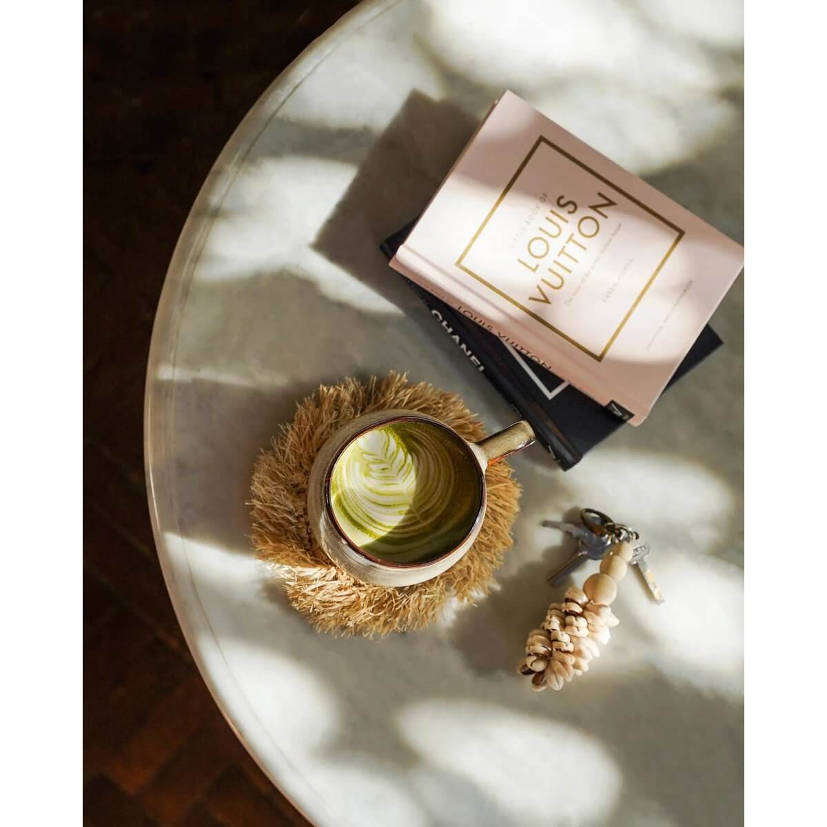 Bohemian style raffia coaster on table with book and mug, perfect for neutral interior decor. Great for both indoor and outdoor use.