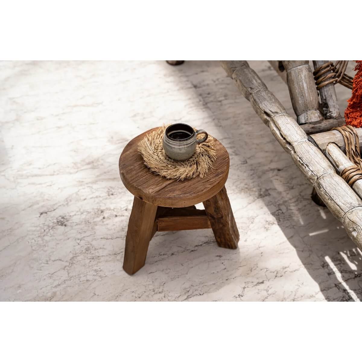 Bohemian style setting with The Fringe Raffia Coaster and coffee cup on a rustic wooden stool.