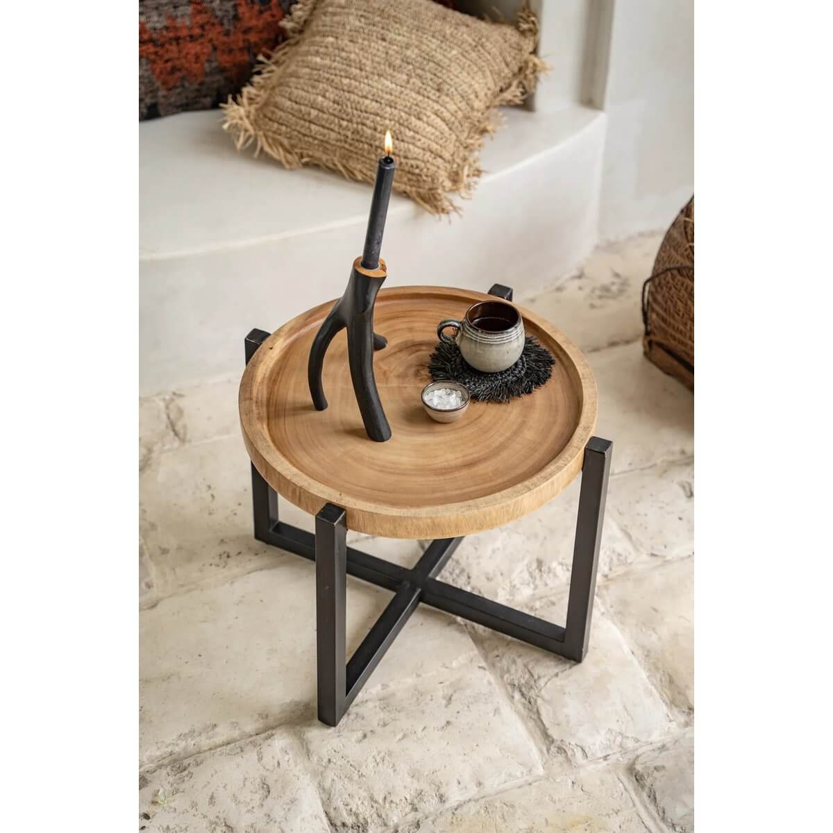 The Fringe Raffia Coaster - Zwart on a rustic coffee table setting with a candle and cup, perfect for a bohemian home decor touch.