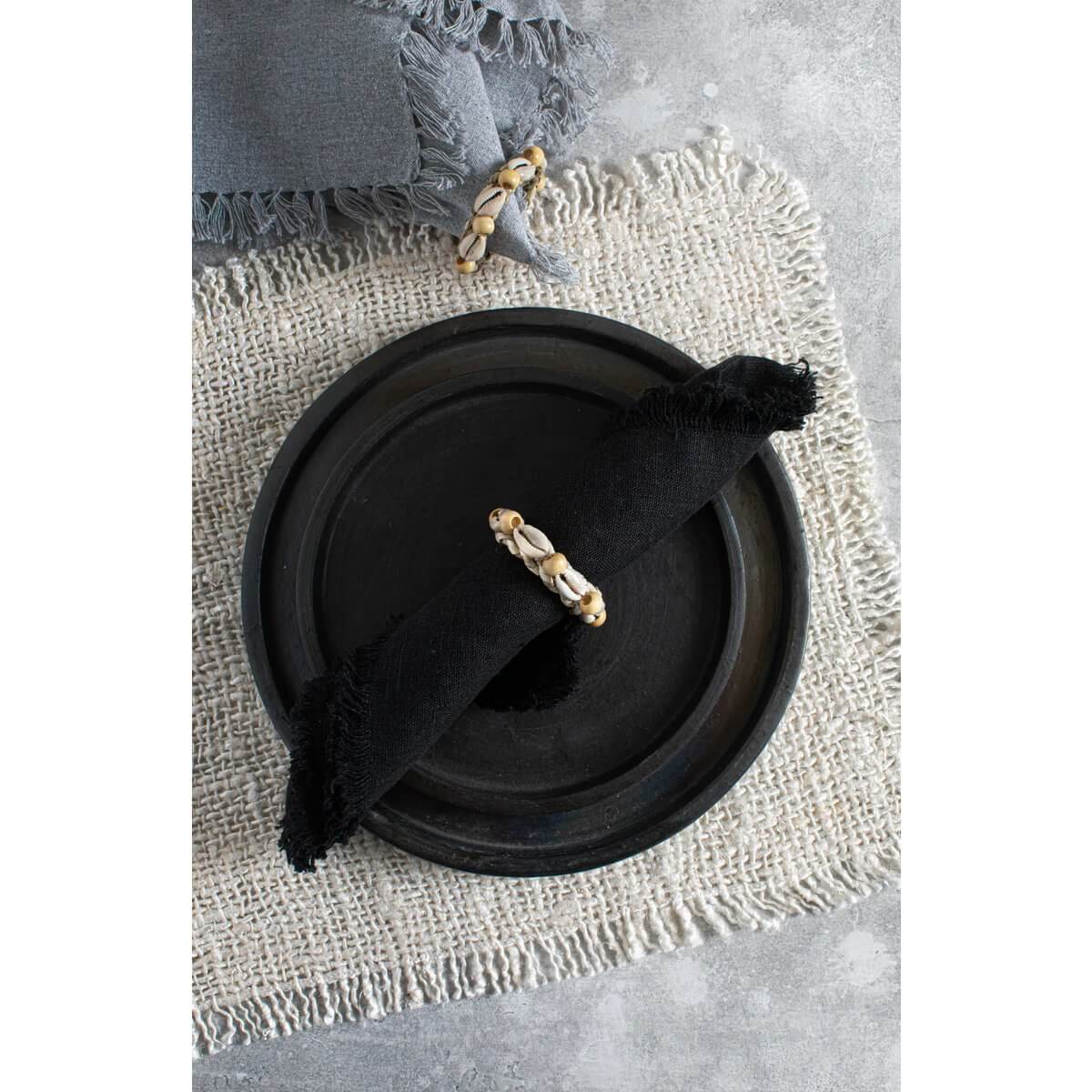 Placemats in crème met wafelstructuur, met een zwarte servet en servetring, decoratieve en luxe tafelschikking.
