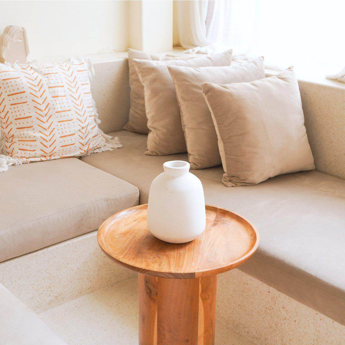 Decoratieve witte kleivaas Bawa op houten tafel in stijlvolle zithoek met zachte kussens, ideaal voor bohostijl inrichting.