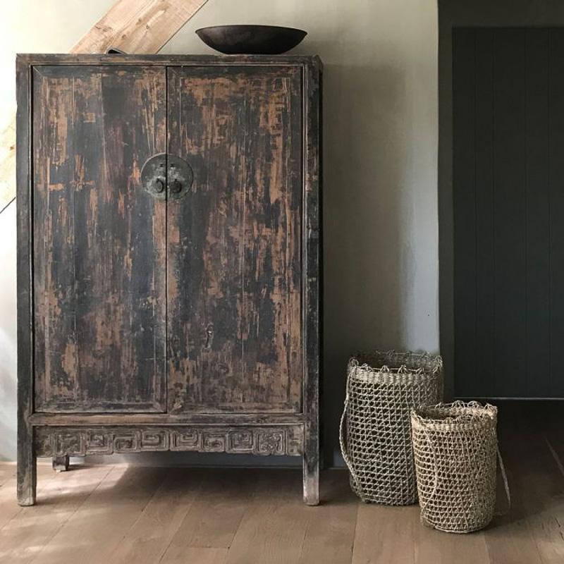 Naturel zeegras mand Julia naast rustieke houten kast in interieur, met organische stijl en tijdloze uitstraling.