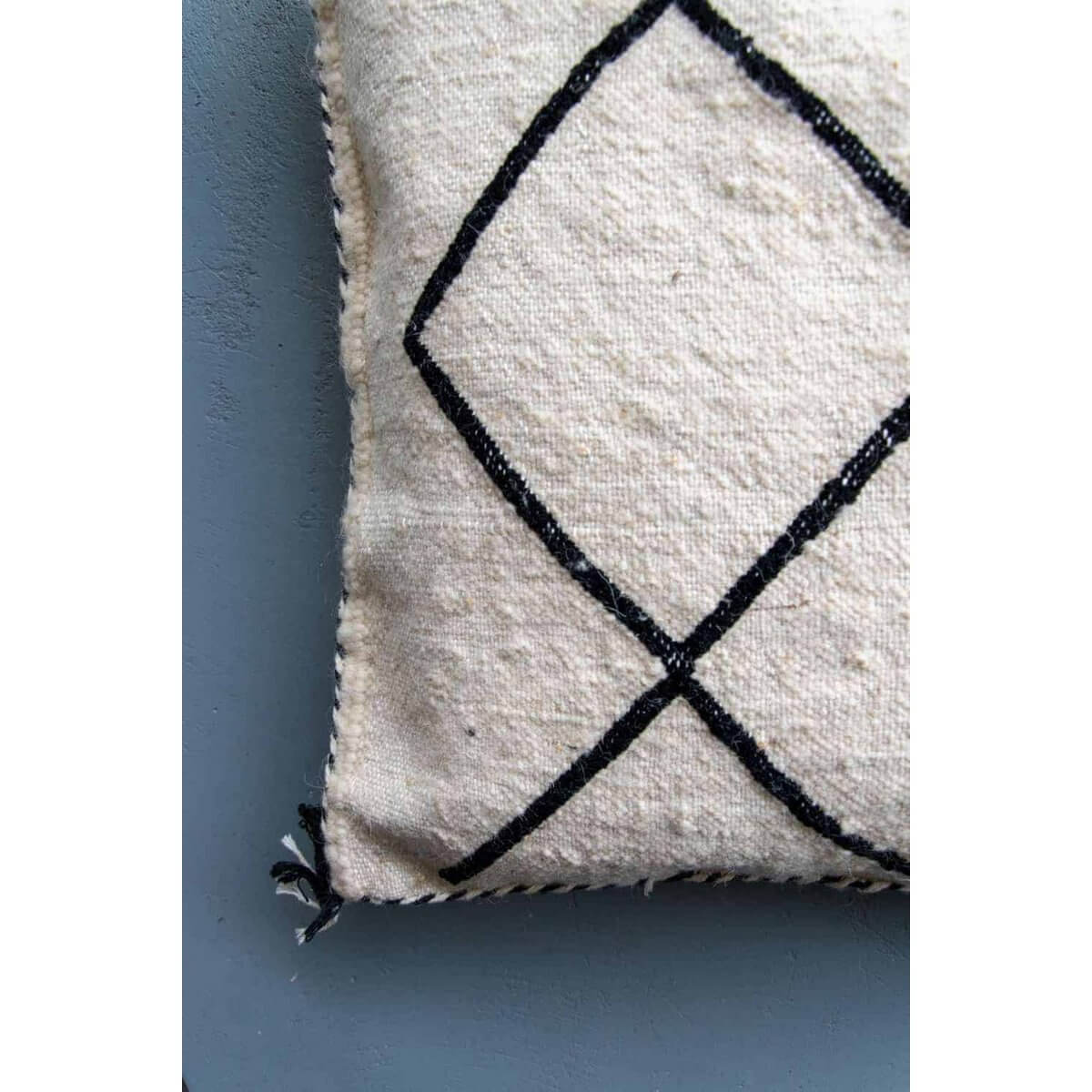 Beni Ouarain kussen met zwart-wit geruit patroon en gestikte zijkanten tegen een grijze achtergrond, perfect voor modern interieur.