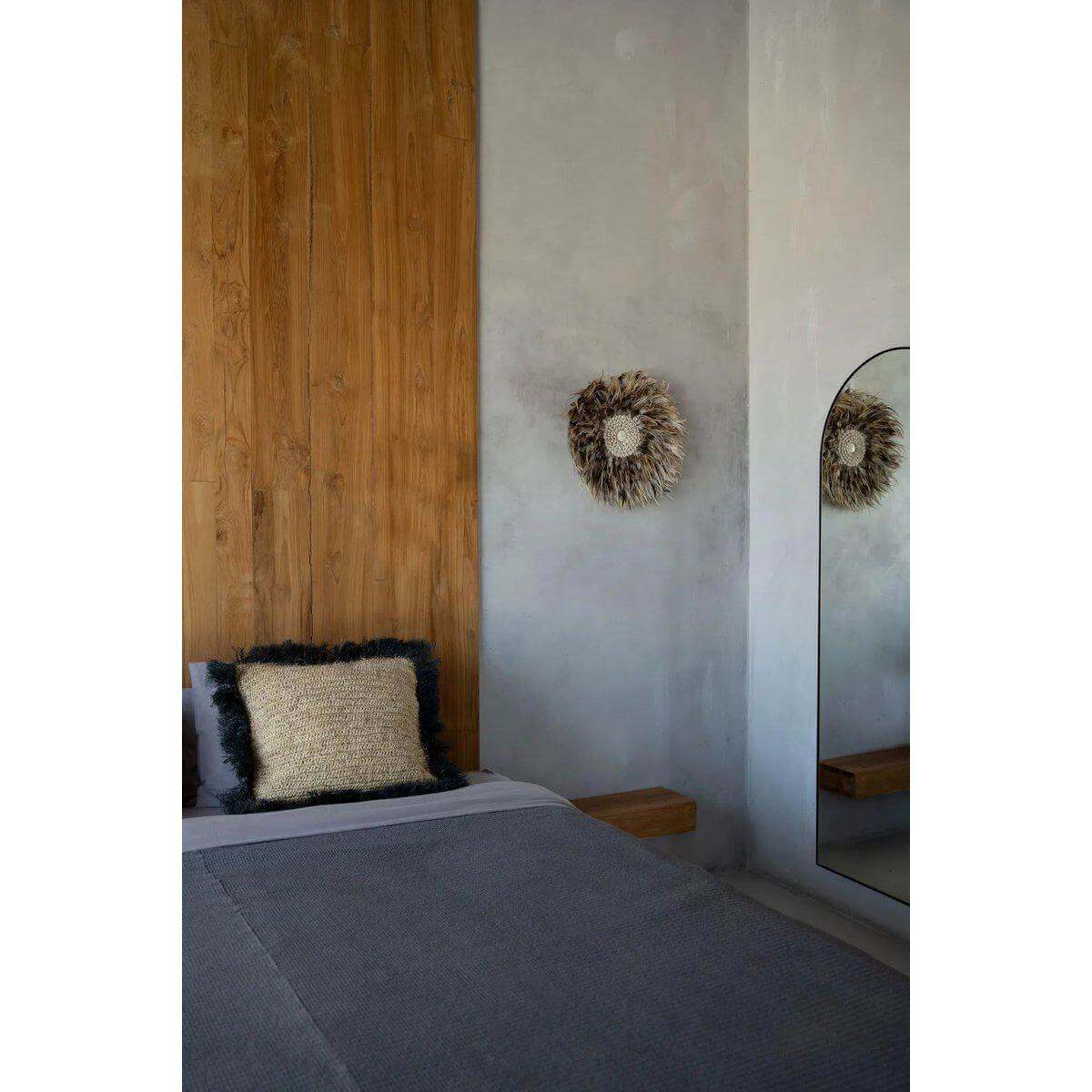 Grijsbruine wanddisplay met veren en schelpen op houten muur in boho-stijl slaapkamer van Bazar Bizar Living.