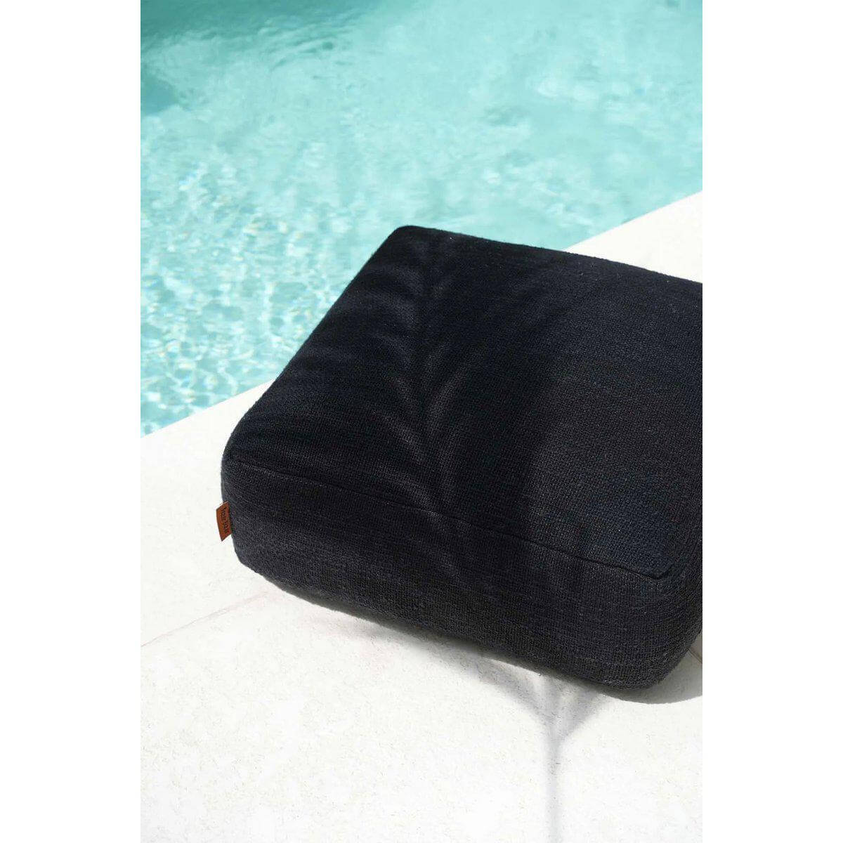 Stijlvolle zwarte poef bij zwembad, perfect voor comfort in huis. Ideale aanvulling voor woonkamer of slaapkamer inrichting.