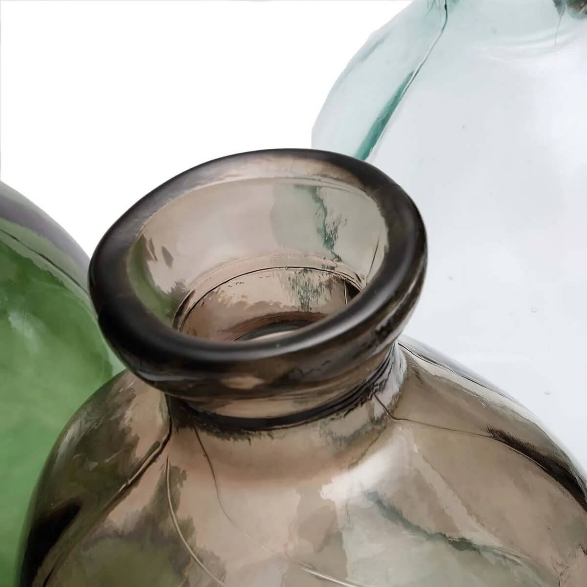 Close-up of a trio of elegant, organically shaped vases in transparent green and beige, showcasing their smooth, bohemian style.