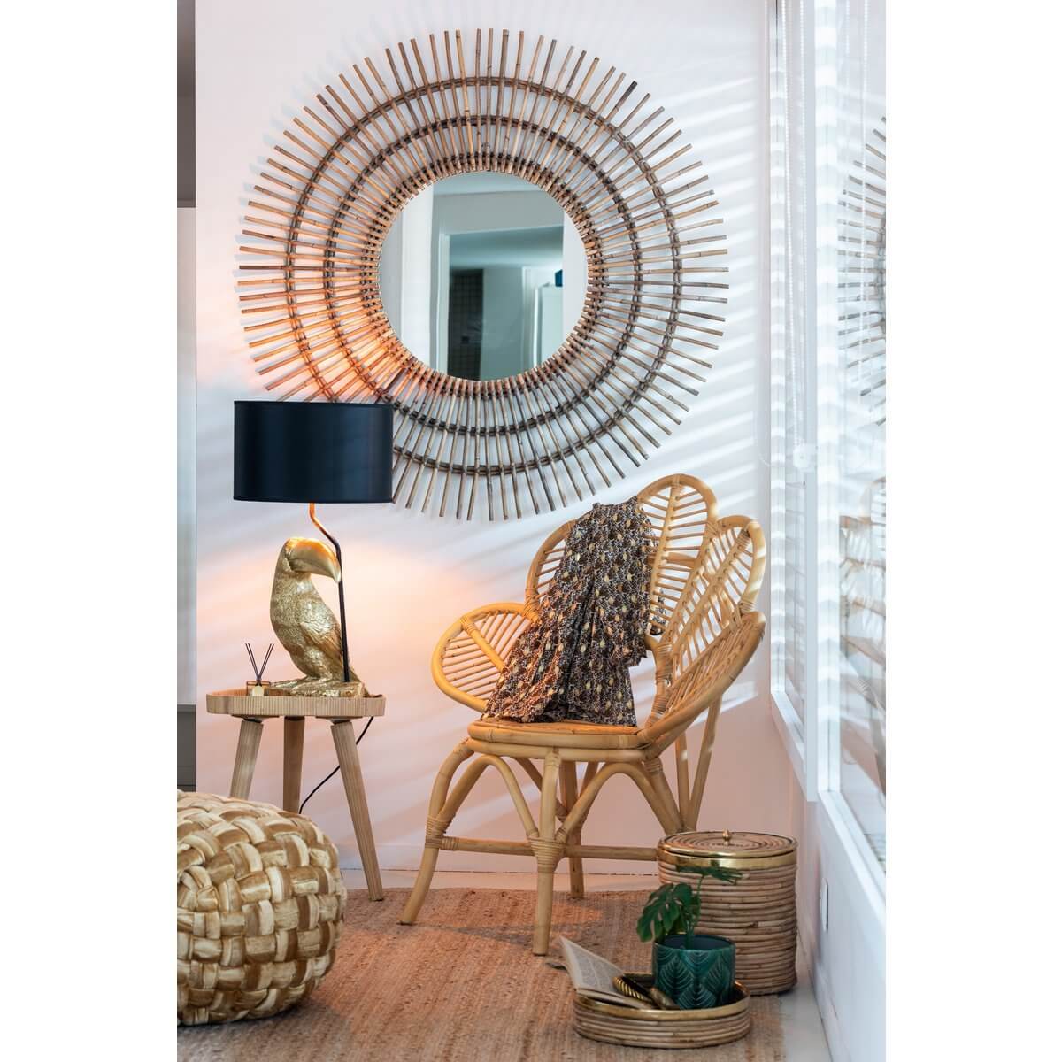 Gezellige hoek met rotan stoel, bijzettafel, schelpachtige spiegel en sfeervolle verlichting in een stijlvol interieur.