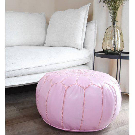 Roze Marokkaanse leren poef als voetenbank in een moderne woonkamer. Perfect voor een boho sfeer en extra zitplaats.