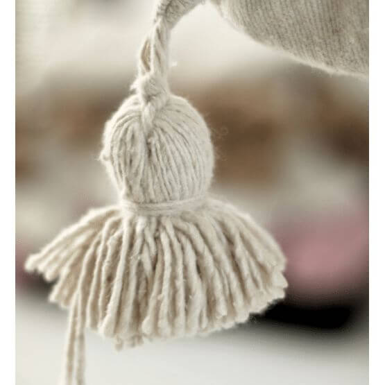 Detail van een crèmekleurige pompom aan een Marokkaanse pompondeken, perfect voor een bohemien sfeer in huis.