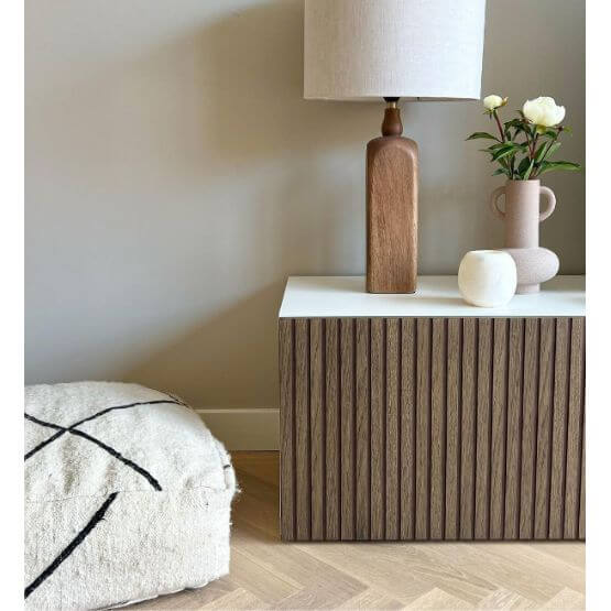 Stijlvolle hoek met Beni Ouarain vloerkussen, moderne houten kast, lamp en bloemenvaas voor woonkamerinrichting.