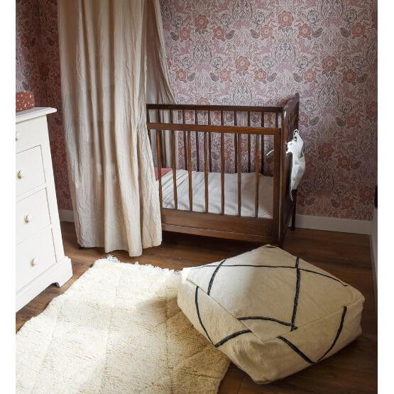 Kinderkamer met Beni Ouarain vloerkussen, houten kinderbed en bloemenbehang. Een stijlvolle en comfortabele interieurkeuze.