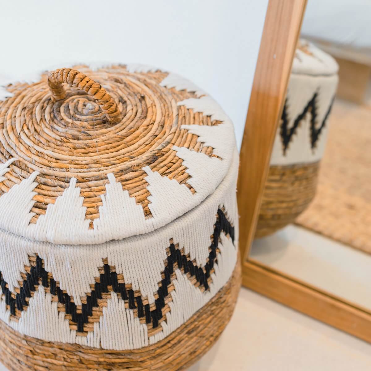 Ronde Boho wasmand PALEM met deksel, handgemaakt van bananenvezels en katoen, gestyled in een moderne interieursetting.
