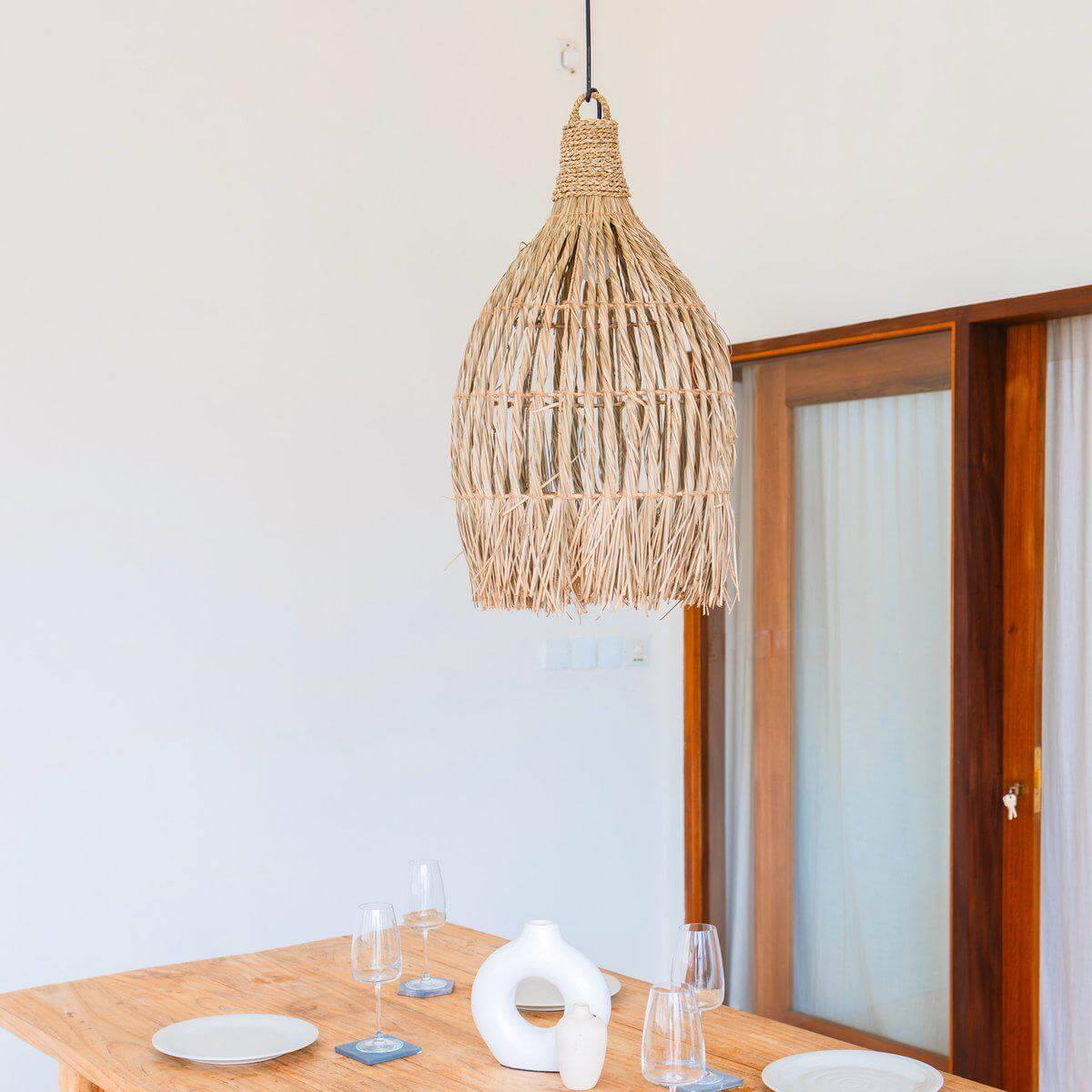 Handgeweven zeegras hanglamp in boho-stijl boven eettafel, creëert warme en gezellige sfeer met natuurlijk lichtspel.